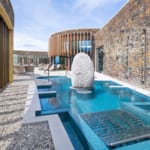 Outdoor spa pool at headland Hotel with stone walls and seating area